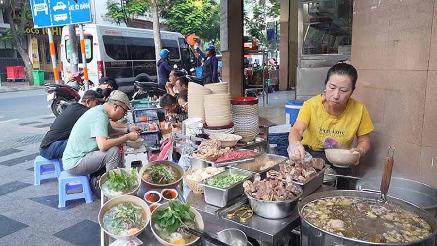 Vendor preparing Pho on a bustling street corner